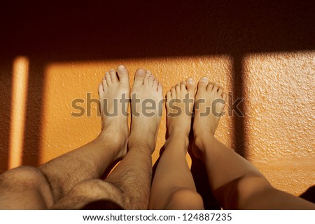 Couple acting naughty in bed - View of a couple\'s feet on the wall