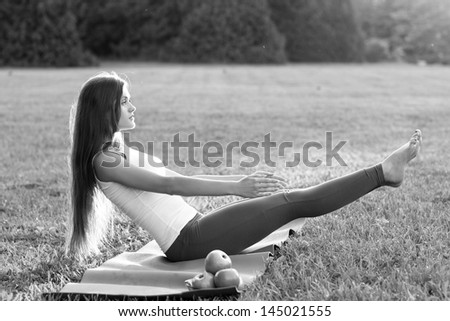 yoga woman with apples on green grass. Outdoor/ Black and white