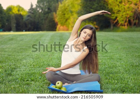 young woman practicing yoga on mat . Outdoors. healthy food.
