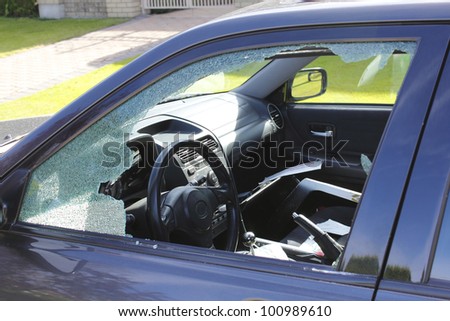 The driver\'s window has been smashed and the interior vandalized/Auto Theft/A vandalized car in an urban setting