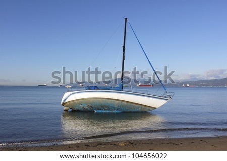 A marooned sailboat on a calm surface/Marooned Sailboat/A marooned sailboat tipped on its side