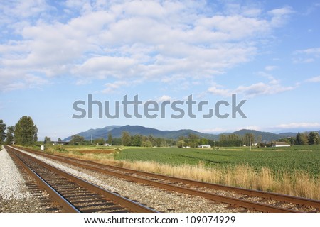 Straight and narrow railway tracks cut across a rural community/Railway Line in a Rural Community/Straight and narrow railway tracks cut across a rural community.