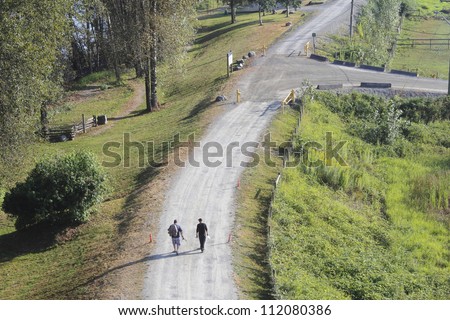 Two fishermen walk down a country road/Fisherman on a Country Road/A relaxed day of fishing as two fishermen walk on a country road.