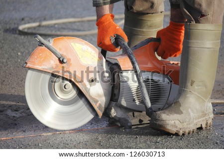Profile on the blade of an asphalt or concrete cutter and workers boots/Profile on Asphalt Cutter/Profile on the blade of an asphalt or concrete cutter and worker\'s boots.