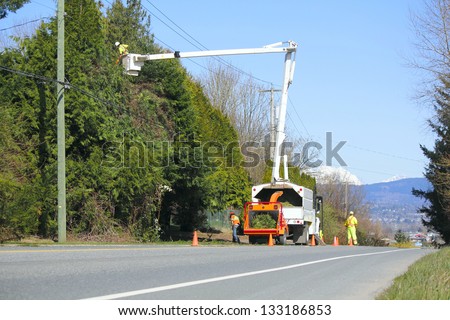 A flag person stands at the crest of a hill while a crew trims trees/Traffic Safety/A flag person stands at the crest of a hill while a crew trims trees