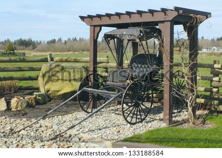An antique buggy is creatively displayed in front of a pasture/Old Antique Buggy/An antique buggy is creatively displayed in front of a pasture.