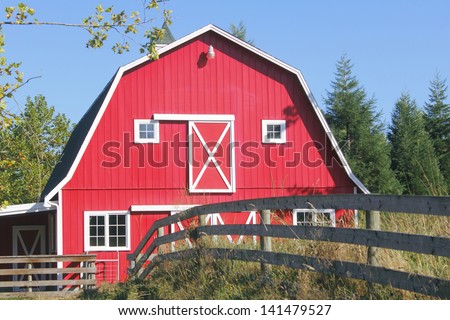 A traditional bright red barn with a white picket fence/Traditional Red Barn/A traditional North American red barn with a white picket fence.