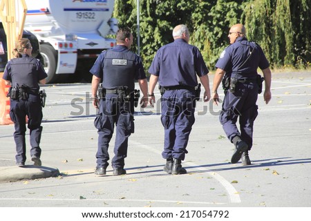 ABBOTSFORD, BC/CANADA - SEPTEMBER 8th: Four Canadian Border Service officers patrol the vehicle line-up at the Sumas border crossing on September 8th, 2014.