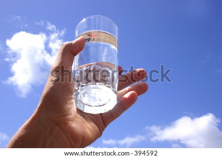 Glass of water in hand with blue sky