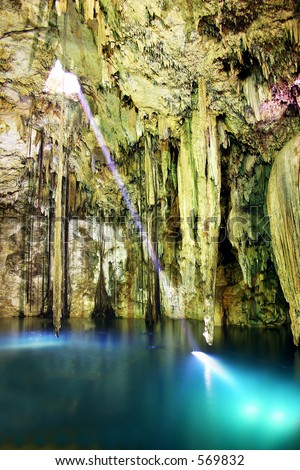 Cave interior with stalactites and beam of light hitting water