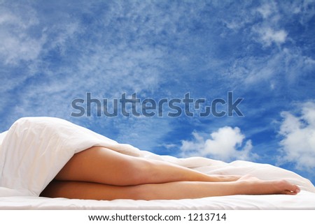 Woman in bed with blue sky showing through the window behind