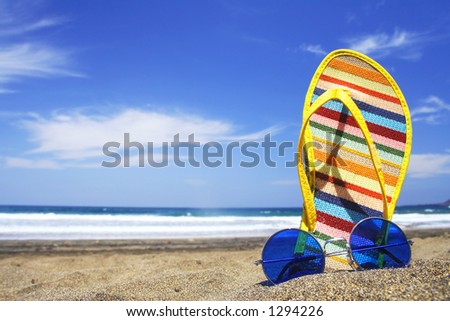 Sunglasses and beach shoes on the beach on a bright day