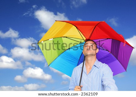 Man in shirt under bright umbrella with blue sky and clouds background