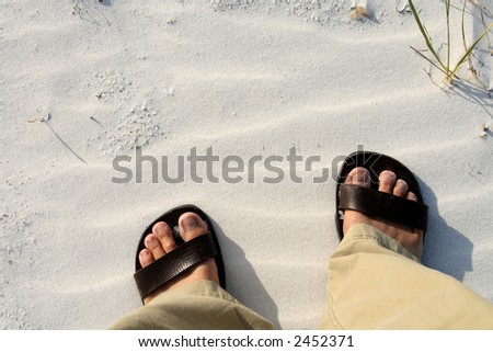 Feet in walking sandals on rippled sand