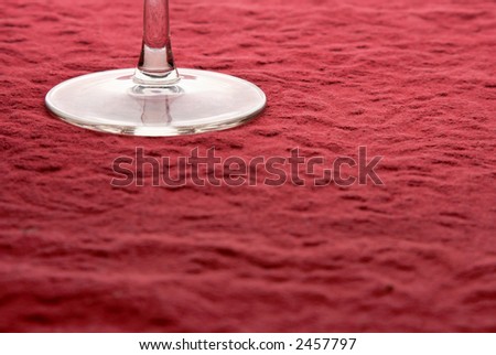 Base of wine glass on rough red table cloth