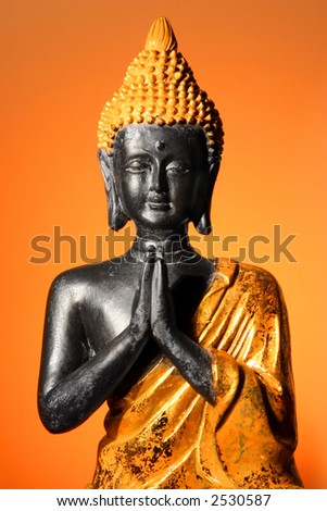 Buddha sculpture at prayer with orange glow background