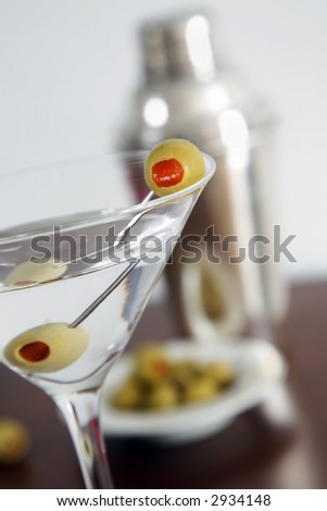 Vodka martini and cocktail shaker. Focus is on the foreground olive