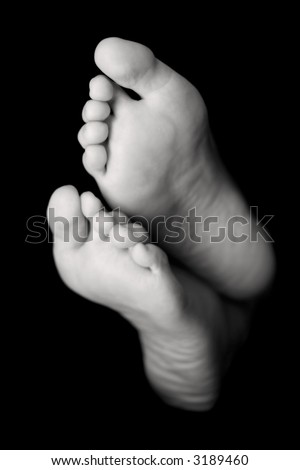 Woman\'s feet in high key over black. Focus is on the toes of teh top foot.