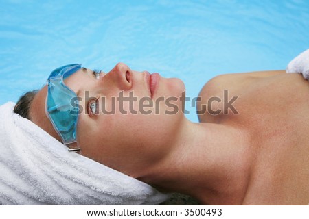 Woman in white towels relaxing by blue pool