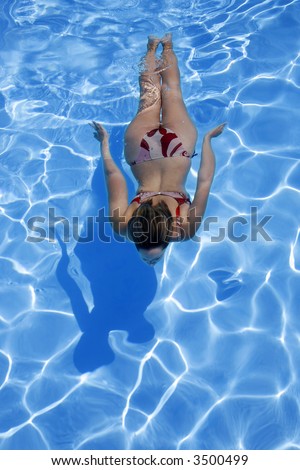 Woman in bikini diving into bright blue pool
