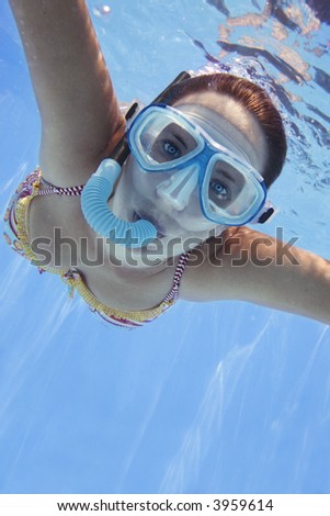 Girl in bikini swimming underwater in blue pool