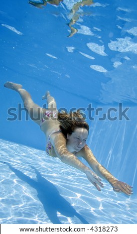 Pretty girl in bikini swimming underwater in blue pool