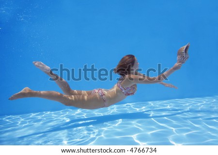 Woman in bikini underwater swimming with conch