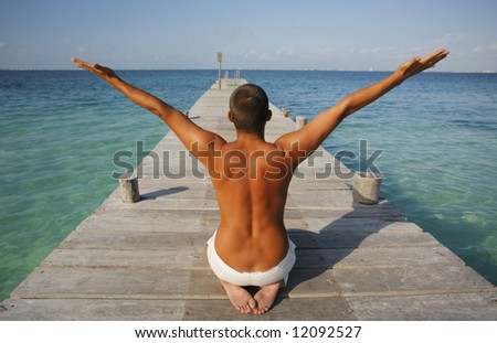 Man in yoga position on a wooden pier