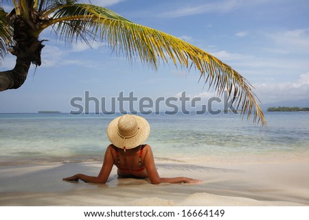 Woman sunbathing under a coconut palm leaf on a paradise island