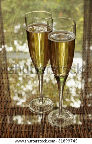 Two champagne glasses bathed in green light on a summer terrace