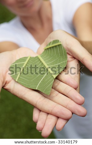Environmental concept shot with a green leaf heart in hands