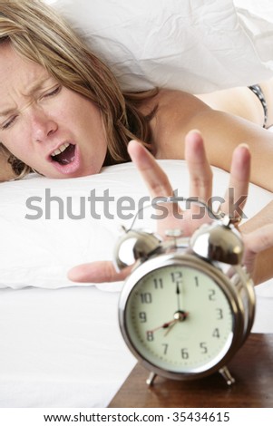 Woman waking up late and reaching for her alarm clock