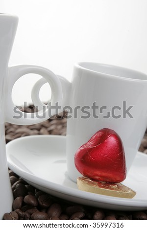 Two coffee cups with a small red chocolate heart