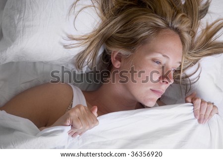 Woman asleep in bed wrapped in white sheets
