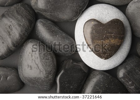 Heart shaped pebble framed on a dark pebble background