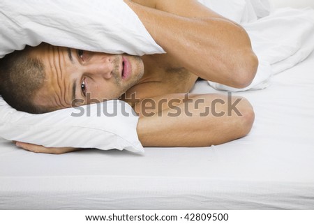 Man trying to sleep with a pillow over his head