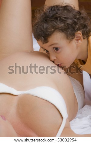 S small boy kisses his mother\'s pregnancy bump