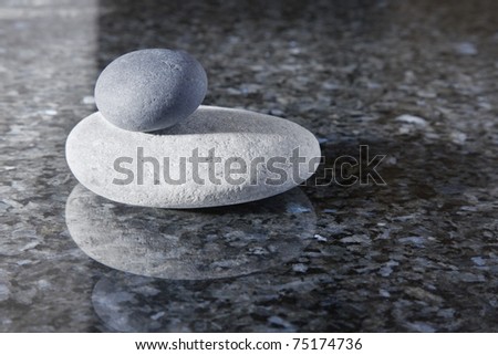 Stack of zen pebbles on a shiny marble surface