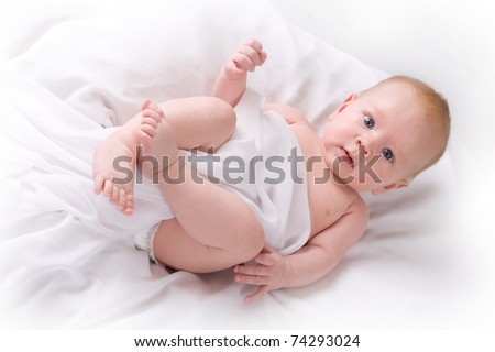 High key studio shot of happy 3 to 4 month old baby boy laying on his back looking at the camera