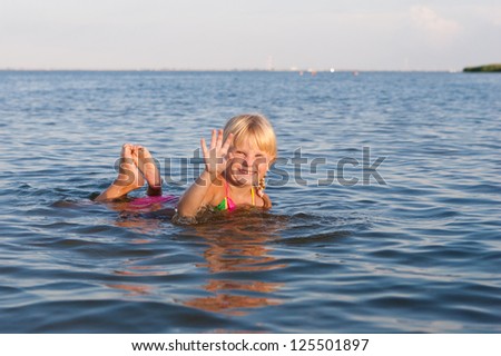 happy girl waving with hands in the water at the evening