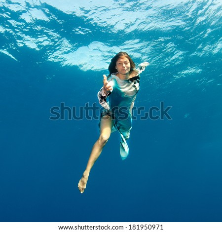 Girl holding out her hand underwater.