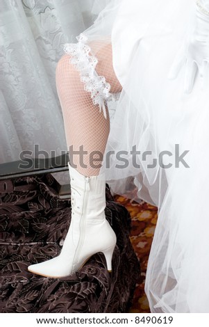 a sexy leg of the bride in a open-work stocking, garter and a white boot