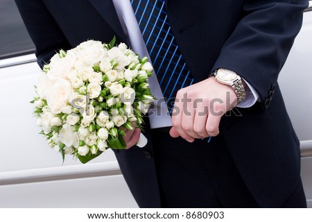 a man in suit with watch hands a flower bouquet