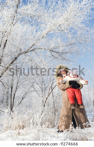 mother plays with her child in a beautiful winter forest