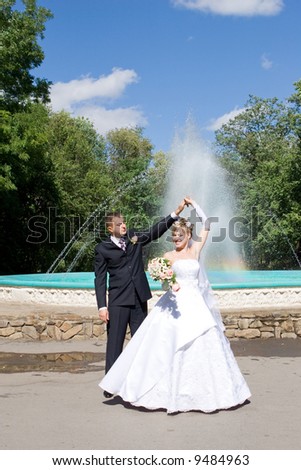 a bride and a groom dance near the fountain