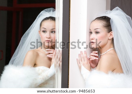 a beautiful bride seriously looks in the mirror