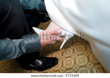 a hand of a man helps a girl to put on a white shoe on her foot