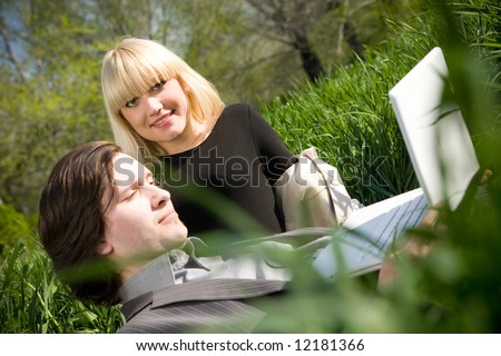 a young business man and business woman working on laptop in nature on the grass field