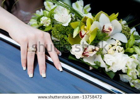 hand of the bride with wedding ring on the car and flower bouquet