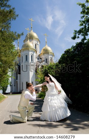 groom kisses hand of bride near the church